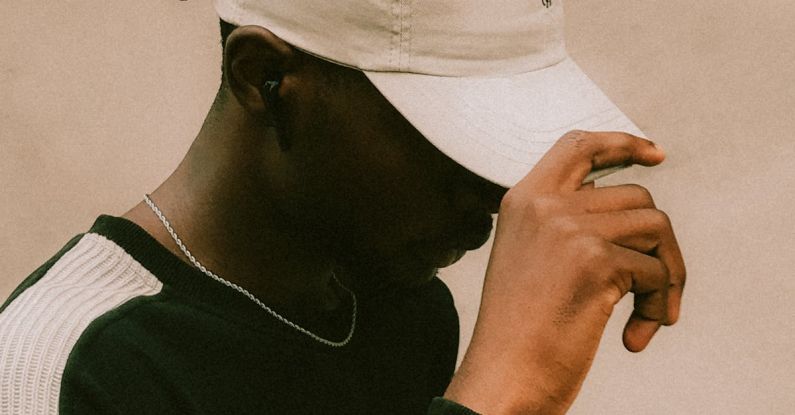 Streetwear Collaborations - A man in a hat and sweater is looking at his phone