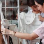 Sustainable Apparel - Trendy young Asian women choosing cotton bags in fashion boutique