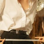 Vintage Designer Clothing - A Woman Looking at the Atelier while Measuring Her Waist