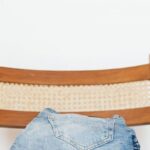Vintage Denim - Stack of blue jeans of different shades on modern wooden chair against white wall