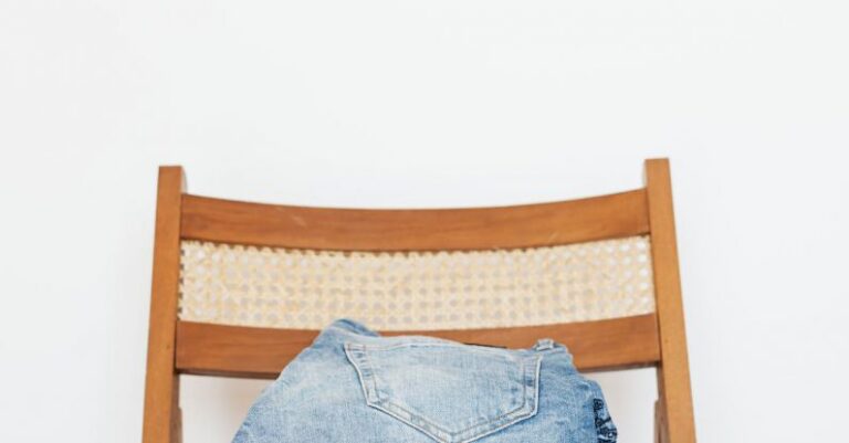 Vintage Denim - Stack of blue jeans of different shades on modern wooden chair against white wall