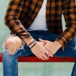 Evolution Of Jeans - Handsome Man in Shirt and Jeans Sitting on Red Bench