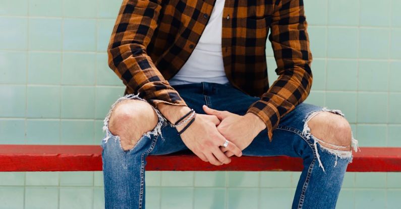 Evolution Of Jeans - Handsome Man in Shirt and Jeans Sitting on Red Bench